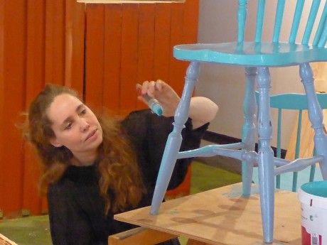 Utställningsproducent Johanna Lisberg Jensen målar den rätta turkosa färgen på Pettsons stolar.