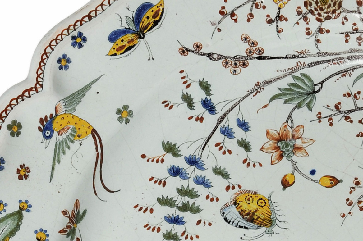 Stort franskt fat i fajans gjort 1740 i Rouend. Blomstermåleriet med fåglar visar ett tydligt inflytande från kinesiska porslinsdekorer.