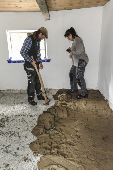 Kulturens medarbetare Örjan Hörlin och Jessica Ljung lägger ut lerskiktet och jämnar till det med klubbor och träskor med brädor under. Foto: Viveca Ohlsson/Kulturen