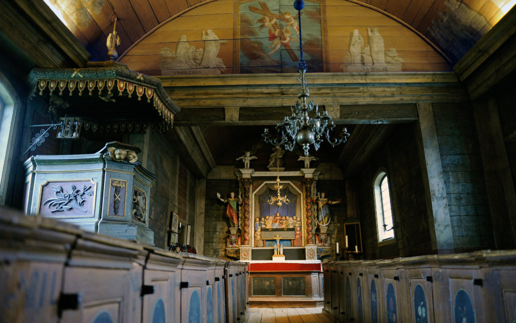 Bosebo kyrkas interiör, med predikstol och altartavla och tak- och väggmålningar från 1700-talet.