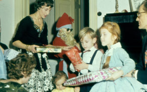 Julklappsutdelning, flera barn med paket, tomte och ett par vuxna