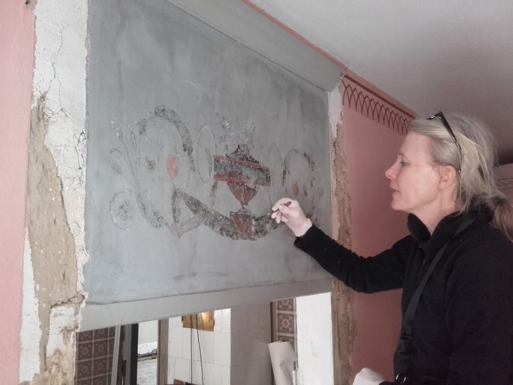 Ingrid Wedberg från Skånes Målerikonservatorer arbetar med väggmålningen i Thomanderska husets sängkammare.