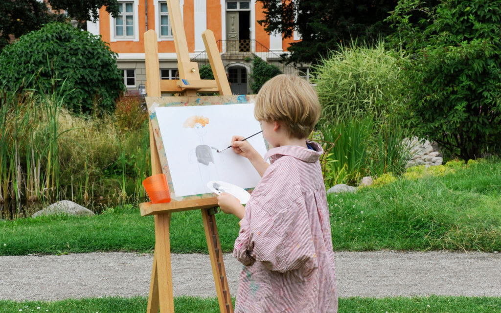 Pojke målar tavla i museet utanför Herrehuset