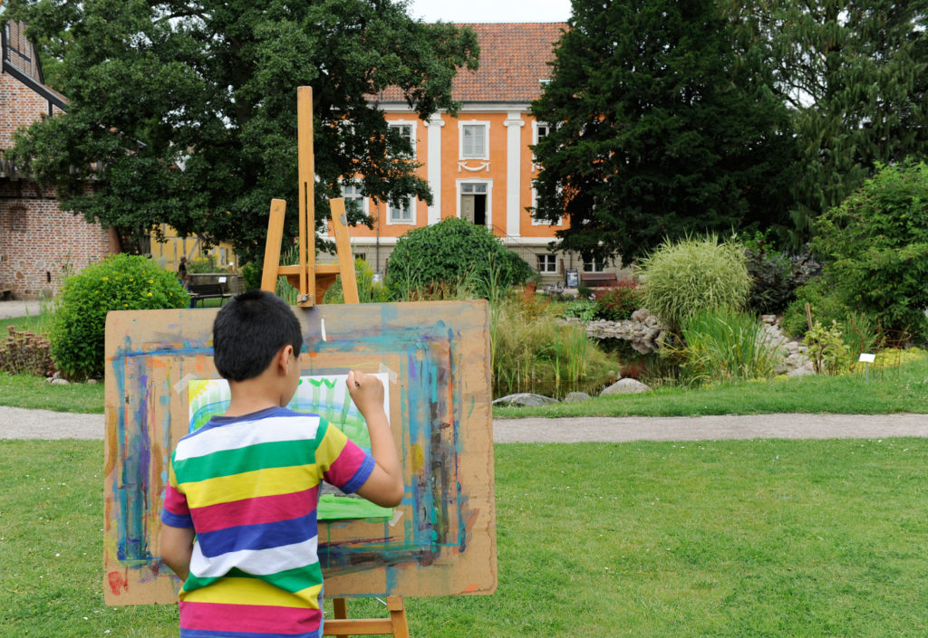 Pojke målar tavla med utsikt över Herrehuset
