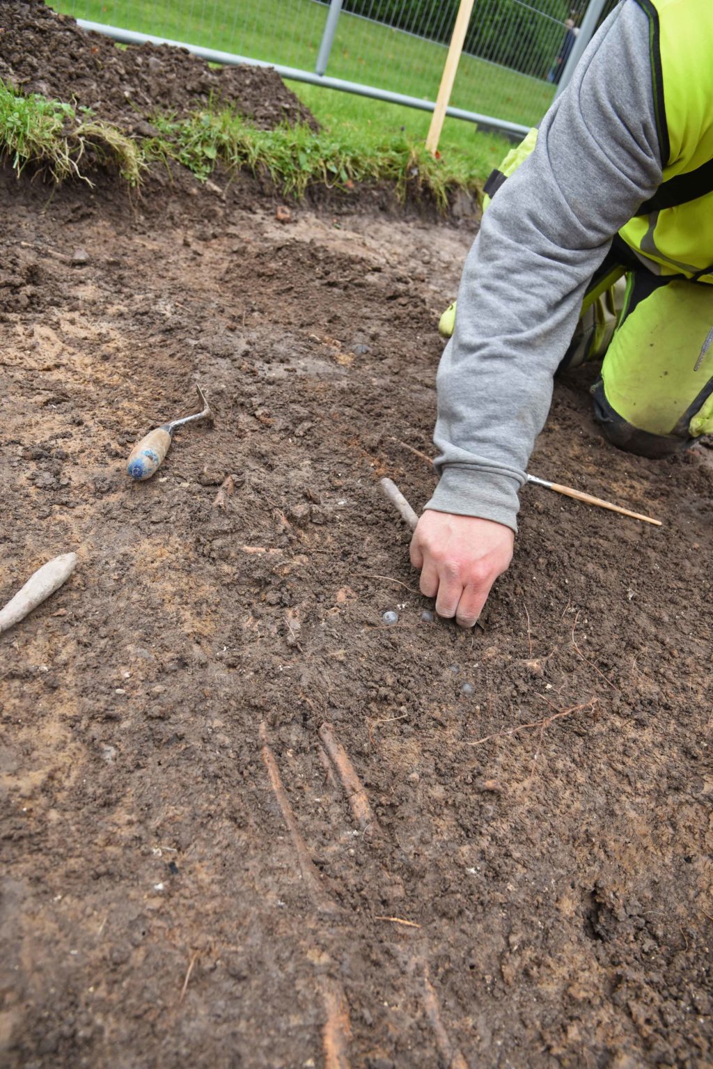 Arkeolog Mattias Karlsson rensar fram pärlorna vid den arkeologiska undersökningen av S:t Olofs kyrkogård