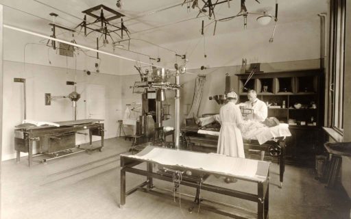 Undersökning vid det nya röntgeninstitutet i Lund, färdigt 1918. Högspänningskablar hänger fritt i isolatorer i taket. Fotograf: Per Bagge.