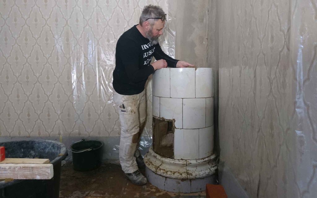 Murarmästare Henrik Nilsson monterar upp kakelugnen i matsalen igen.