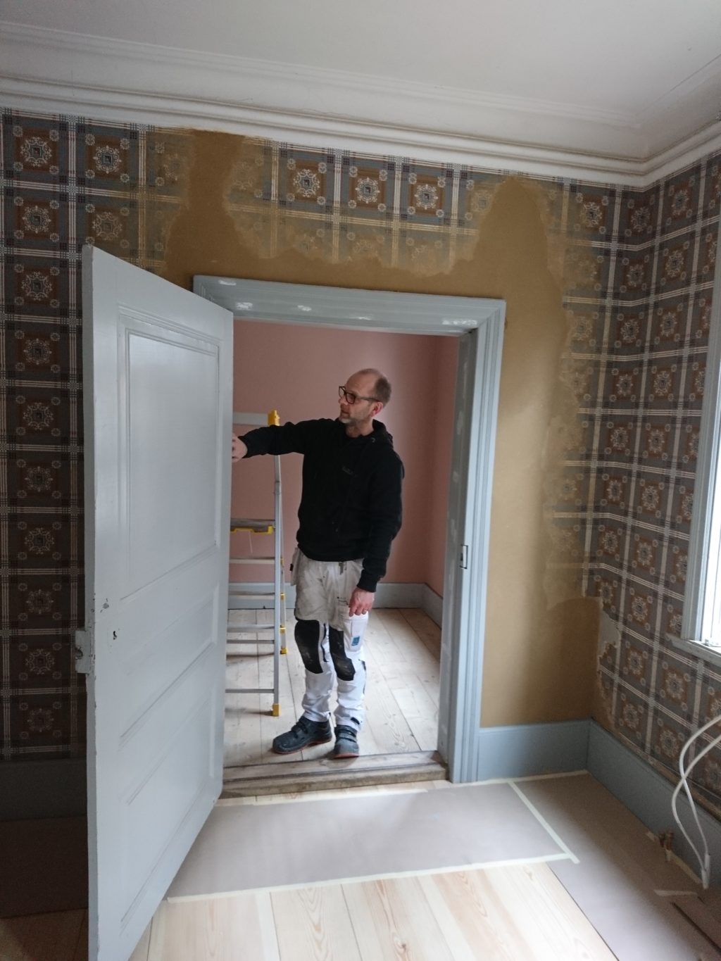Målare Rickard Öhman i dörröppningen mellan förmaket och sovrummet. 