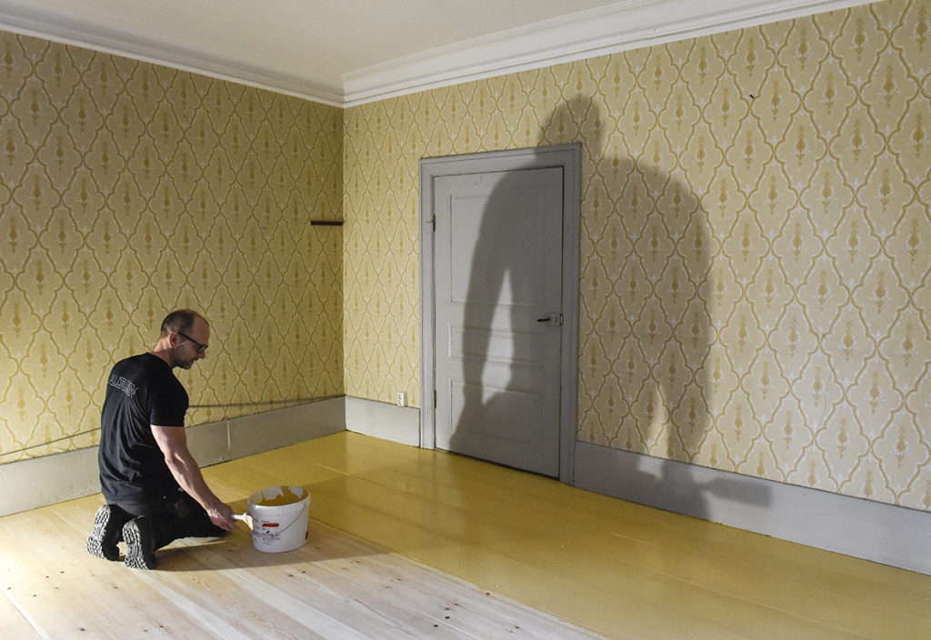 Kulturens målare Rickard Öhman målar matsalsgolvet gult.