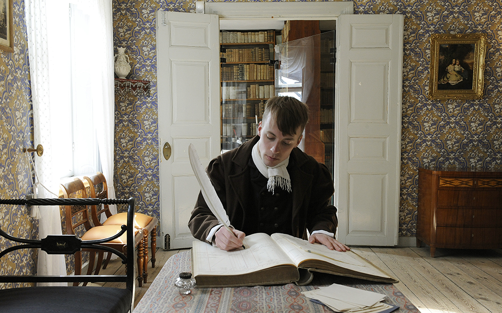 A man writing at a table in The Thomander House at Kulturen in LUnd