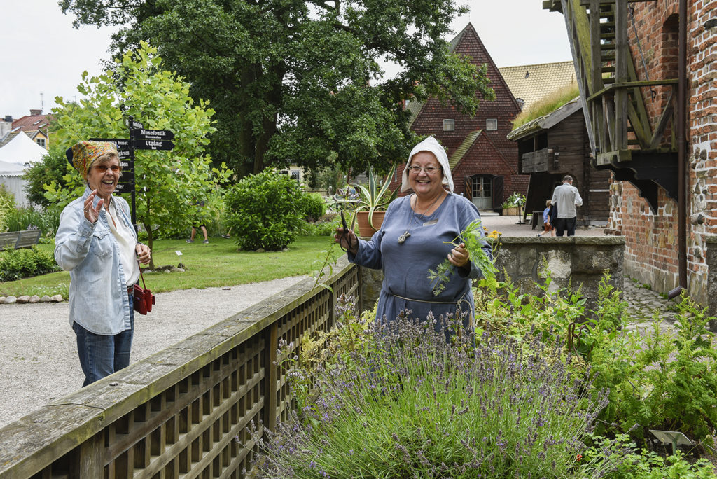 En besökare möter en av våra volontärer i Örtagården, som hör till det medeltida Dekanhuset. 
