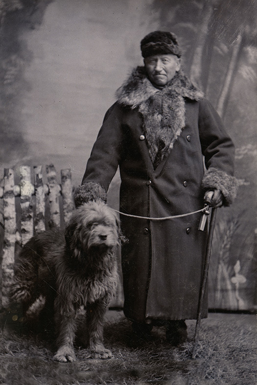 Väktaren Henrik på Tuna slott i Lund med sin vakthund. Fotograf August Korfitzen, Mårtenstorget, Lund, 1876–1896. Ur Kulturens samlingar.
