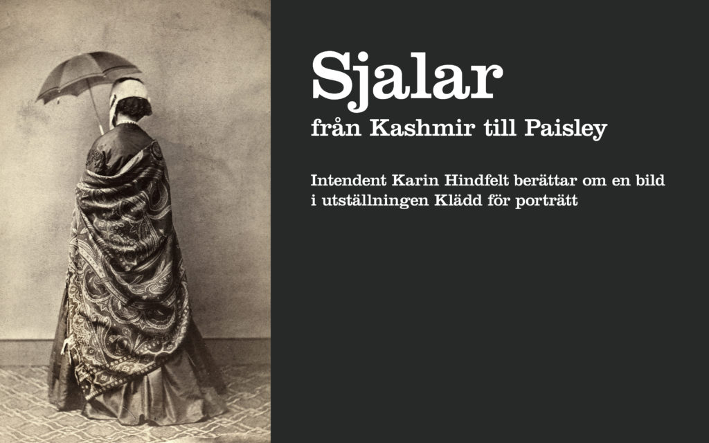 Fotografi från 1860-talet på kvinna med ryggen vänd mot betraktaren. Hon är klädd i klänning och en stor paisleysjal och håller i ett parasoll. Från utställningen Klädd för porträtt på Kulturen i Lund.