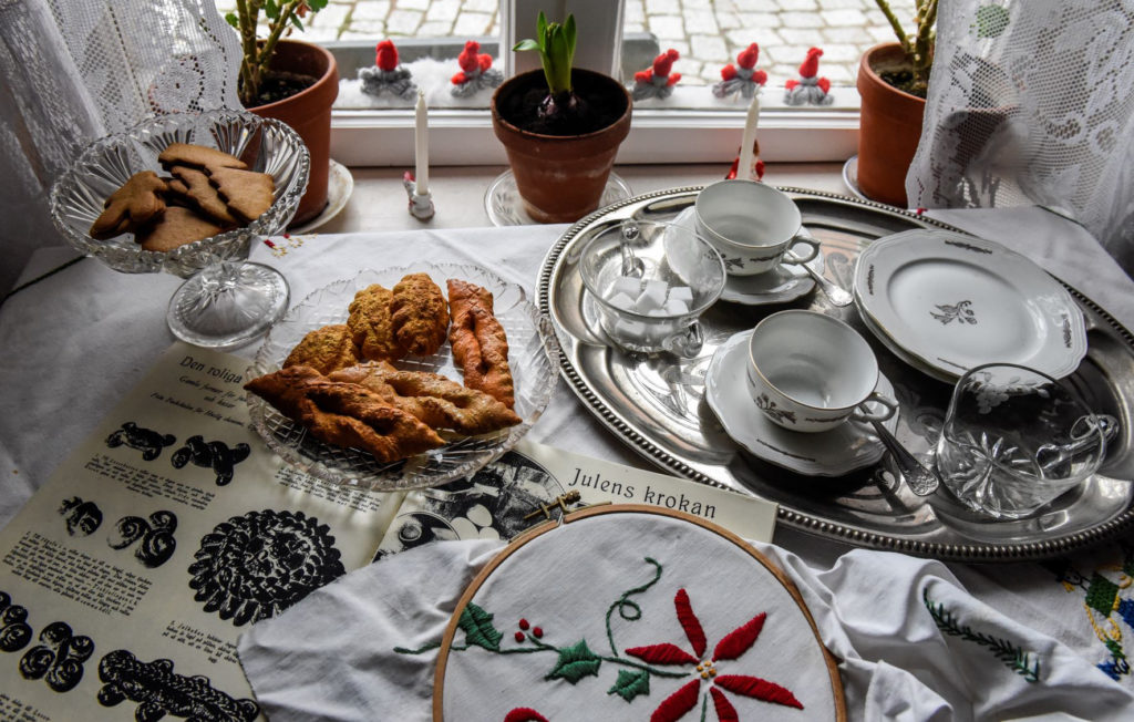 fikat står framdukat på bordet vid fönstret: mandelmusslor, klenätter och pepparkakor med kaffekoppar redo. Här ligger också ett julbroderi och jultidningar från 1930. 
