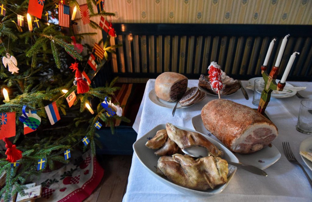 Granen är dekorerad med flaggspel, tomtar med mera. På bordet står julljusstaken i form av en tomte, och julmaten är framdukad. 