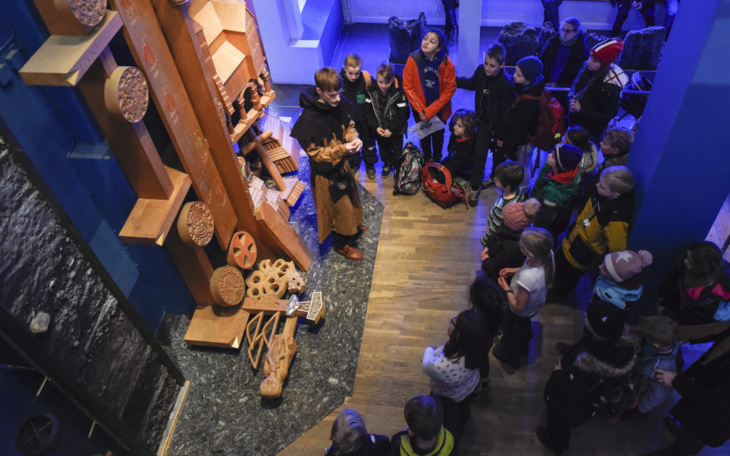 Pedagog Olle Ekström med besökande barn i utställningen Metropolis – Lund på medeltiden.