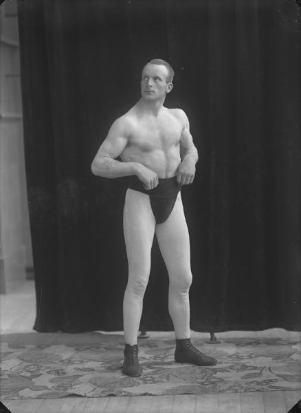 Fotografi av poserande man med bar överkropp och träningsbyxor. Foto: Ida Ekelund, ur Kulturens samlingar.