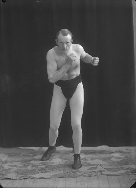 Fotografi av poserande man med bar överkropp och träningsbyxor. Foto: Ida Ekelund, ur Kulturens samlingar. KM 93676.3467