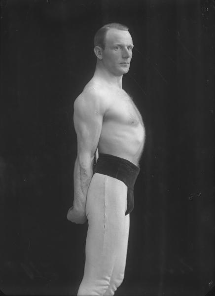 Fotografi av poserande man med bar överkropp och träningsbyxor. Foto: Ida Ekelund, ur Kulturens samlingar. 