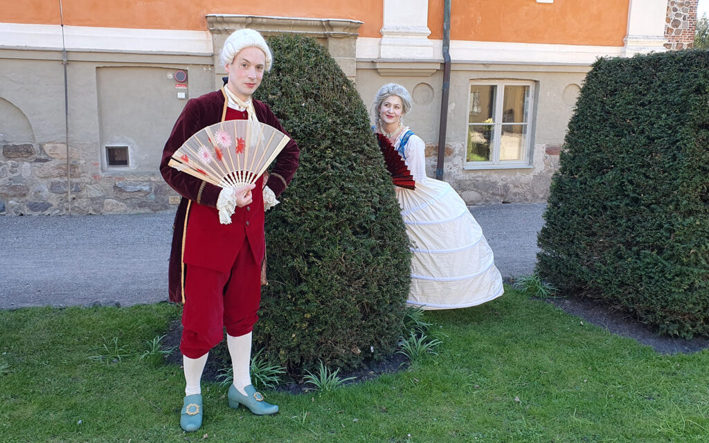 En man och en kvinna i 1700-talskläder i friluftsmuseet på Kulturen i Lund