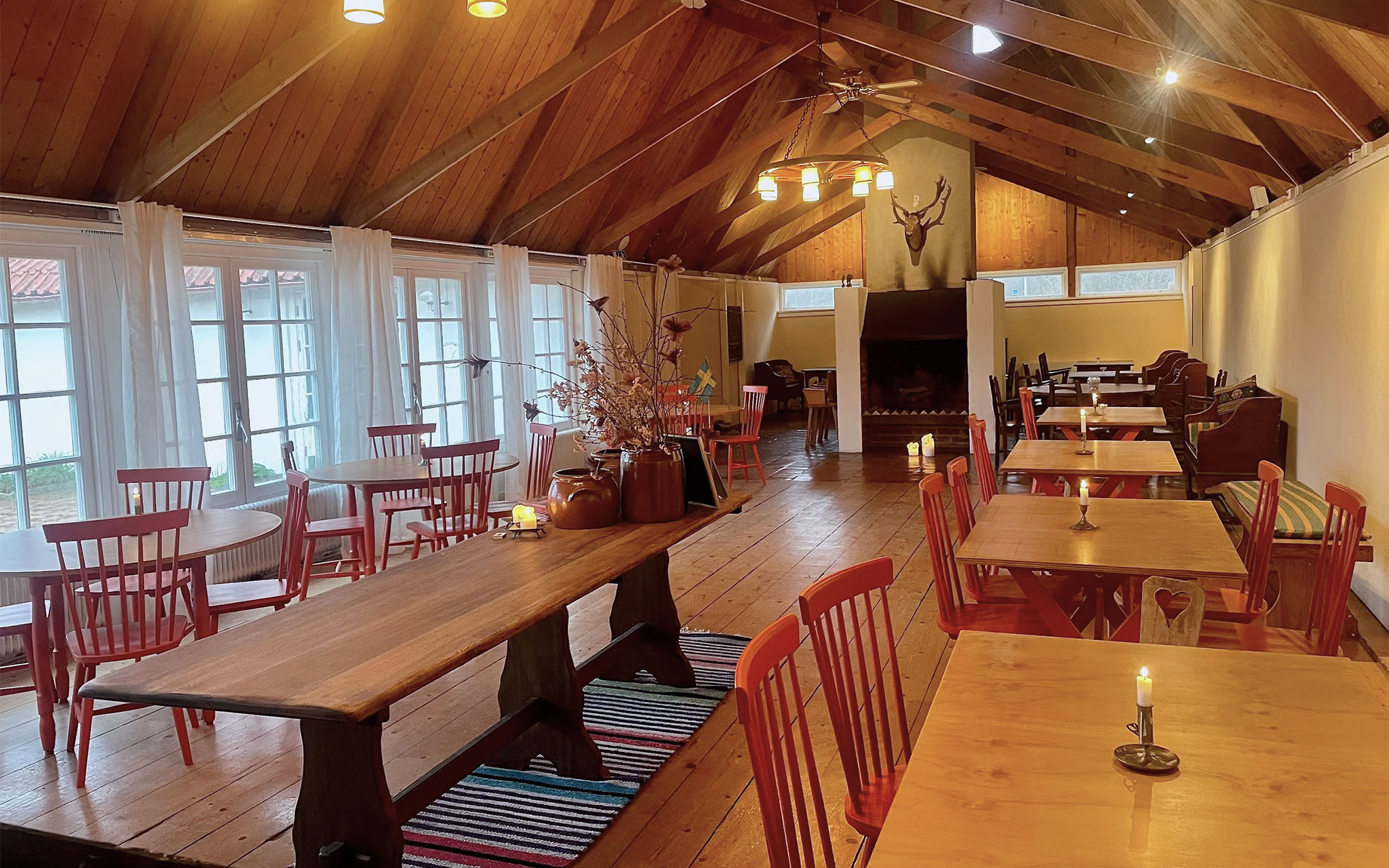 En lokal möblerad som ett café, med träbord och röda stolar.